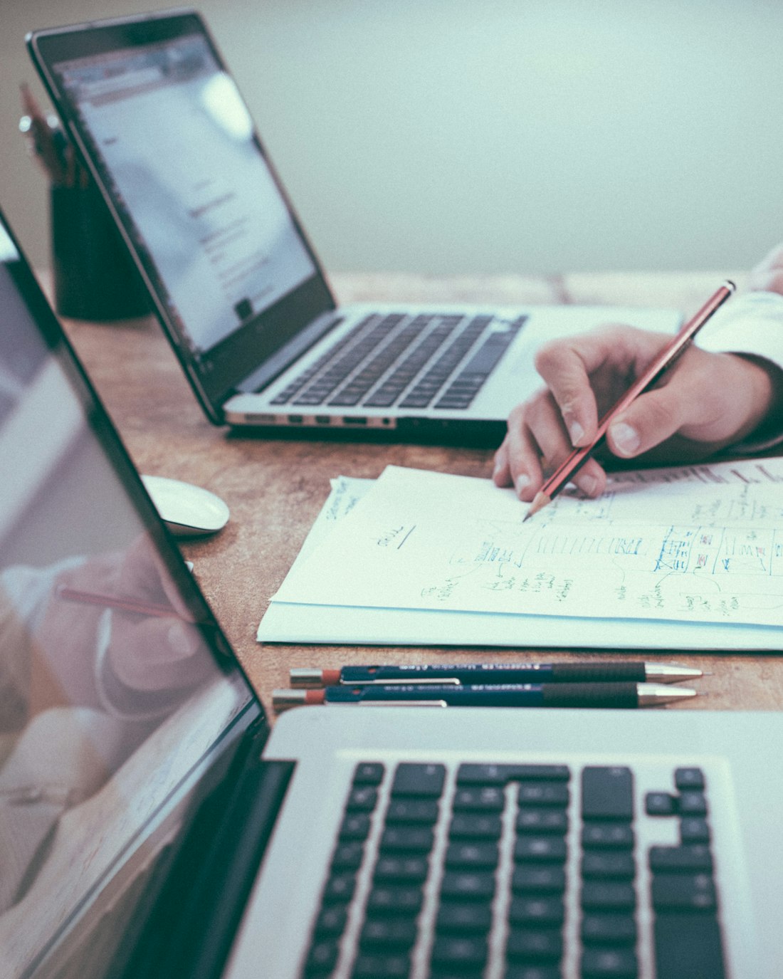 A tidy desk with an open laptop, a notebook and a cup of coffee